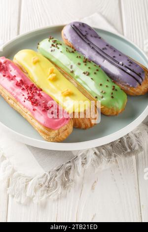 Gruppe französischer Dessert Eclair Nahaufnahme auf Teller auf hölzernem Hintergrund. Vertikal Stockfoto