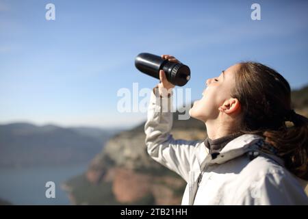 Wanderer trinkt aus der Flasche, die in der Natur steht Stockfoto
