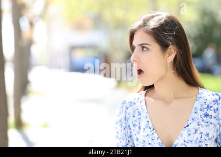 Überraschte Frau, die auf die Seite blickt, die auf der Straße steht Stockfoto