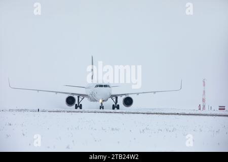 Verkehr am Flughafen bei Schneefall. Passagierflugzeug, das an frostigem Wintertag zum Start auf die Start- und Landebahn fährt. Stockfoto