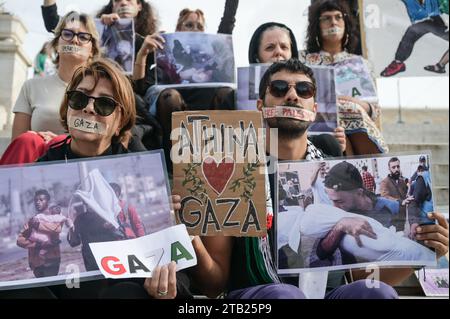 Athen, Griechenland. 3. Dezember 2023. Demonstranten mit aufgeklebtem Mund halten ein Banner mit der Aufschrift Athina - Athen liebt Gaza. Pro-palästinensische Demonstranten, die ihren Mund zugehalten haben und Bilder von Kriegsgrausamkeiten in Gaza halten, demonstrieren am Sonntag vor dem griechischen Parlament. Quelle: Dimitris Aspiotis/Alamy Live News Stockfoto