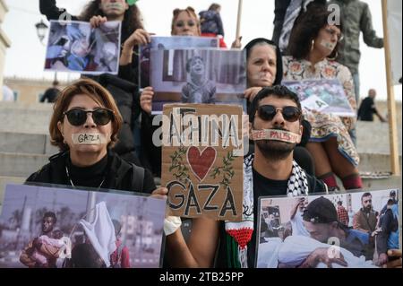 Athen, Griechenland. 3. Dezember 2023. Demonstranten mit aufgeklebtem Mund halten ein Banner mit der Aufschrift Athina - Athen liebt Gaza. Pro-palästinensische Demonstranten, die ihren Mund zugehalten haben und Bilder von Kriegsgrausamkeiten in Gaza halten, demonstrieren am Sonntag vor dem griechischen Parlament. Quelle: Dimitris Aspiotis/Alamy Live News Stockfoto