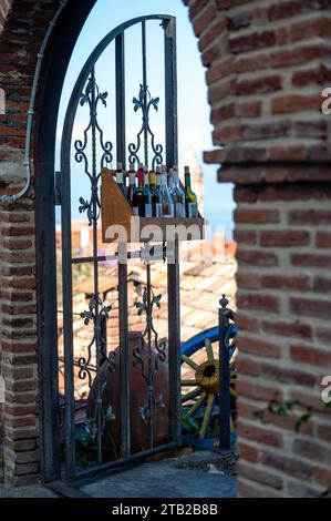 Eine Schachtel Weinflaschen am Eisentor eines Restaurants in der Altstadt von Sighnaghi, Georgia Stockfoto