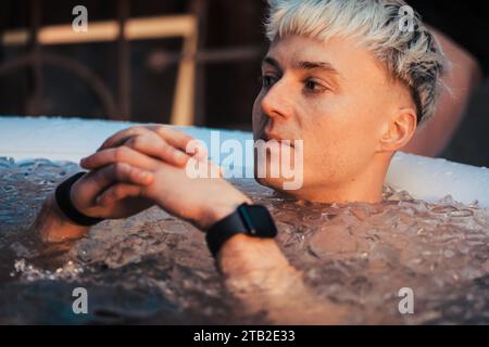 Gutaussehender Junge oder Mann, der im kalten Wasser zwischen Eiswürfeln schwimmt. Wim Hof Methode, Kältetherapie, Atemtechniken, Yoga, Meditation Stockfoto