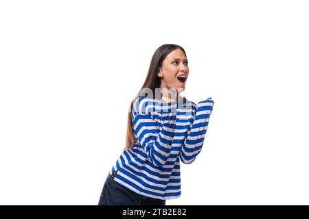 Die junge süße, schlanke Brünette mit glatten Haaren trägt eine blau gestreifte Matrosenjacke Stockfoto
