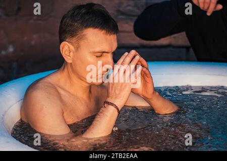 Gutaussehender Junge oder Mann, der im kalten Wasser zwischen Eiswürfeln schwimmt. Wim Hof Methode, Kältetherapie, Atemtechniken, Yoga, Meditation Stockfoto