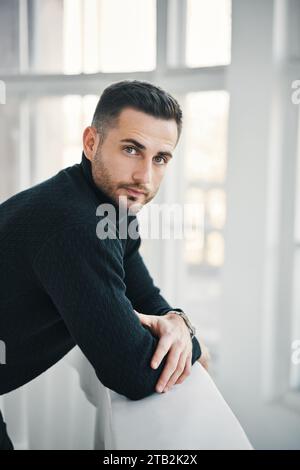 Porträt eines jungen, gutaussehenden Mannes in einem dunklen Rollkragenpullover, der in die Kamera schaut. Männliche Schönheit. Confidence Concept Stockfoto