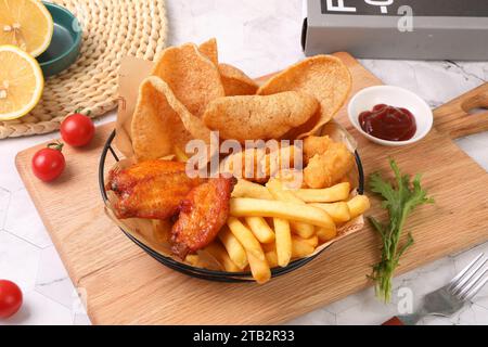 Die Snackplatte umfasst: Pommes frites, gegrillte Hähnchenflügel, Garnelenchips Stockfoto