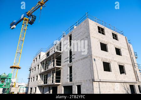 Bau eines luxuriösen Wohnkomplexes: Kran auf der Baustelle und im Bau befindliches Gebäude Stockfoto