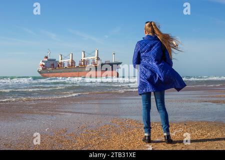 Ein Tourist sieht ein großes Frachtschiff, das während eines Sturms an Land gespült wird und vor der Schwarzmeerküste auf Grund läuft. Stockfoto