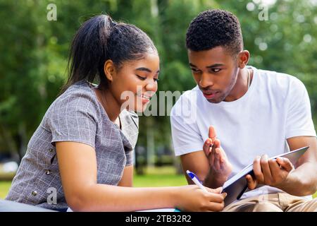 afroamerikanische Freunde teilen ihr Wissen auf dem Universitätscampus an sonnigen Tagen im Park Stockfoto