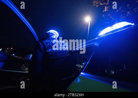 Stuttgart, Deutschland. November 2023 30. Ein Polizist steigt für ein Fotoshooting in ein Polizeiauto (inszenierte Szene). Quelle: Marijan Murat/dpa/Alamy Live News Stockfoto