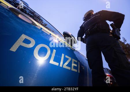 Stuttgart, Deutschland. November 2023 30. Eine Polizistin steht während eines Fotoshootings neben einem Polizeifahrzeug (posierte Szene). Quelle: Marijan Murat/dpa/Alamy Live News Stockfoto