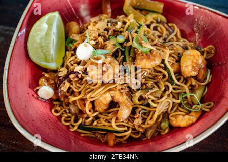 Ein Nahbild einer frisch zubereiteten Garnelennudeln im thailändischen Stil, die in einer roten Schüssel serviert werden. Stockfoto