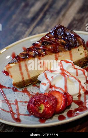 Ein Stück frisch gebackener Käsekuchen mit Schlagsahne und frischen Erdbeeren. Stockfoto