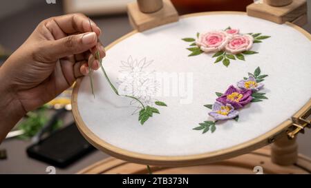 Artistry in Motion: Nahaufnahme eines Handstickens einer Blume auf Stoff mit Hoop-Ständer Stockfoto