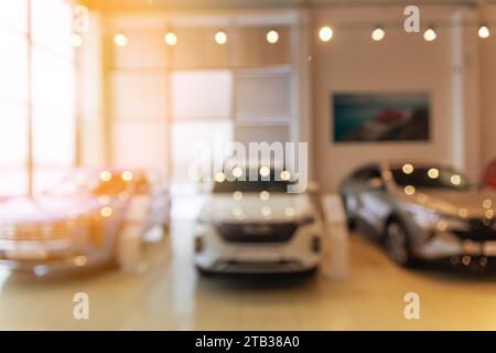 Verschwommenes neues Auto parkt im modernen Ausstellungsraum und wartet auf Verkauf. Abstrakter Hintergrund des unscharfen Platzes des Händlerbetriebs für Neufahrzeuge. Stockfoto