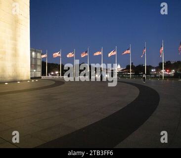 Das Washington Monument ist ein Obelisk in der National Mall in Washington, D.C., das in der Abenddämmerung mit Flaggen um das Denkmal herum zu sehen ist. Stockfoto