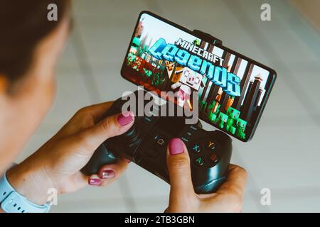 Brasilien. Dezember 2023. In dieser Fotoabbildung wird das Minecraft Legends-Logo auf einem Smartphone-Bildschirm angezeigt, während eine Person auf einem Gaming-Gamepad spielt. Quelle: SOPA Images Limited/Alamy Live News Stockfoto