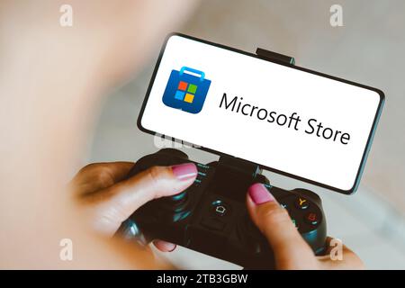 Brasilien. Dezember 2023. In dieser Fotoabbildung wird das Microsoft Store-Logo auf einem Smartphone-Bildschirm angezeigt, während eine Person auf einem Gaming-Gamepad spielt. Quelle: SOPA Images Limited/Alamy Live News Stockfoto