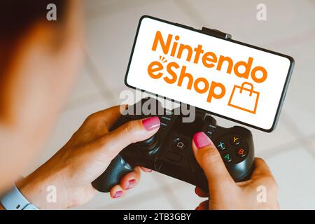 Brasilien. Dezember 2023. In dieser Fotoabbildung wird das Nintendo eShop-Logo auf einem Smartphone-Bildschirm angezeigt, während eine Person auf einem Gaming-Gamepad spielt. Quelle: SOPA Images Limited/Alamy Live News Stockfoto