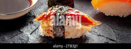 Unagi Sushi, Nigiri mit Aal, Panorama mit Sojasauce auf schwarzem Hintergrund. Japanisches Restaurant Stockfoto