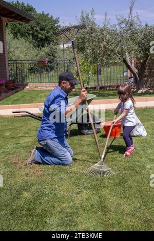 Bild eines müden jungen Vaters, während er und seine kleine Tochter Gartenarbeiten machen Stockfoto