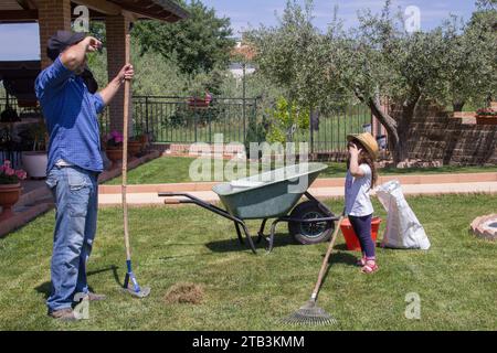 Bild eines müden jungen Vaters, während er und seine kleine Tochter Gartenarbeiten machen Stockfoto