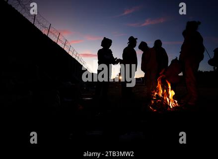 Jacumba Hot Springs, Kalifornien, USA. Dezember 2023. Eine Asylsuchende Migrantenfamilie mit kleinen Kindern aus Columbia versucht, sich neben einem Feuer in einem Freiluftlager an der Grenze zwischen den USA und Mexiko in der Nähe der kleinen Wüstengemeinde Jacumba Hot Springs im San Diego County warm zu halten. Hunderte von Asylbewerbern überqueren täglich die Grenze in die Vereinigten Staaten und erleben kalte Nächte, in denen sie auf ihre Bearbeitung warten. (Kreditbild: © K.C. Alfred/ZUMA Press Wire) NUR REDAKTIONELLE VERWENDUNG! Nicht für kommerzielle ZWECKE! Stockfoto