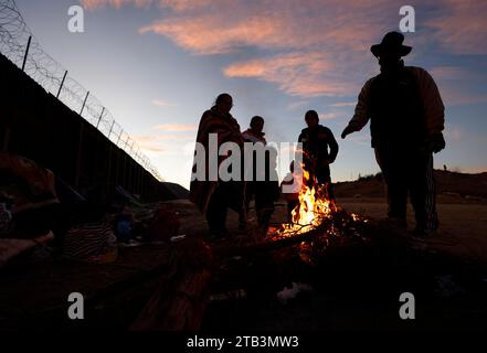 Jacumba Hot Springs, Kalifornien, USA. Dezember 2023. Eine Asylsuchende Migrantenfamilie mit kleinen Kindern aus Columbia versucht, sich neben einem Feuer in einem Freiluftlager an der Grenze zwischen den USA und Mexiko in der Nähe der kleinen Wüstengemeinde Jacumba Hot Springs im San Diego County warm zu halten. Hunderte von Asylbewerbern überqueren täglich die Grenze in die Vereinigten Staaten und erleben kalte Nächte, in denen sie auf ihre Bearbeitung warten. (Kreditbild: © K.C. Alfred/ZUMA Press Wire) NUR REDAKTIONELLE VERWENDUNG! Nicht für kommerzielle ZWECKE! Stockfoto