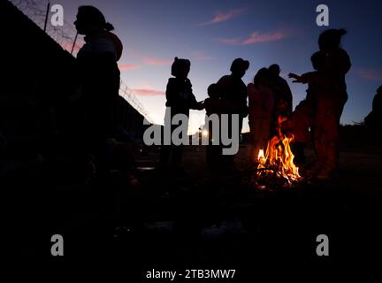 Jacumba Hot Springs, Kalifornien, USA. Dezember 2023. Eine Asylsuchende Migrantenfamilie mit kleinen Kindern aus Columbia versucht, sich neben einem Feuer in einem Freiluftlager an der Grenze zwischen den USA und Mexiko in der Nähe der kleinen Wüstengemeinde Jacumba Hot Springs im San Diego County warm zu halten. Hunderte von Asylbewerbern überqueren täglich die Grenze in die Vereinigten Staaten und erleben kalte Nächte, in denen sie auf ihre Bearbeitung warten. (Kreditbild: © K.C. Alfred/ZUMA Press Wire) NUR REDAKTIONELLE VERWENDUNG! Nicht für kommerzielle ZWECKE! Stockfoto