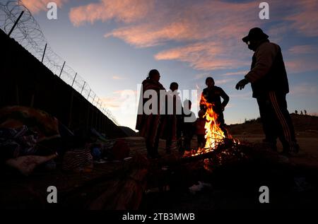 Jacumba Hot Springs, Kalifornien, USA. Dezember 2023. Eine Asylsuchende Migrantenfamilie mit kleinen Kindern aus Columbia versucht, sich neben einem Feuer in einem Freiluftlager an der Grenze zwischen den USA und Mexiko in der Nähe der kleinen Wüstengemeinde Jacumba Hot Springs im San Diego County warm zu halten. Hunderte von Asylbewerbern überqueren täglich die Grenze in die Vereinigten Staaten und erleben kalte Nächte, in denen sie auf ihre Bearbeitung warten. (Kreditbild: © K.C. Alfred/ZUMA Press Wire) NUR REDAKTIONELLE VERWENDUNG! Nicht für kommerzielle ZWECKE! Stockfoto