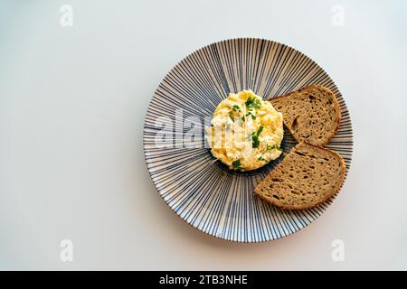 Ein Teller mit Rührei serviert mit braunem Brot Toast aus der Vogelperspektive. Stockfoto