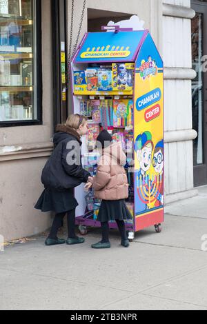 2 bescheiden gekleidete orthodoxe Schwestern schauen sich Spiele und Spielzeug in einem Chanukah Center in Williamsburg, Brooklyn, New York an. Stockfoto