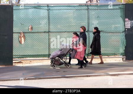 Eine orthodoxe Frau und ihre 4 Kinder laufen an einer Baustelle auf der Lee Avenue in Williamsburg, Brooklyn, New York vorbei. Stockfoto
