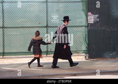 Ein chassidischer Junge und seine jüngere Schwester gehen an der Lee Avenue in Williamsburg, Brooklyn, New York vorbei. Stockfoto