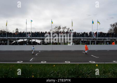 Zwei Marshals stehen auf der Start-Ziel-Straße und warten darauf, dass Autos anstehen, 80. Mitgliederversammlung, Goodwood Motor Racing Circuit, Chichester, Großbritannien Stockfoto