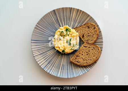 Ein Bild von frisch gerührten Eiern, serviert mit braunem Toast. Stockfoto