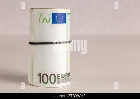 Eine Rolle von hundert Euro-Banknoten steht auf einem Tisch vor hellem Hintergrund aus nächster Nähe Stockfoto