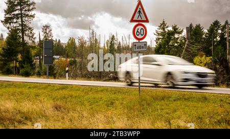 Weißes Auto fährt schnell auf den Landstraßen mitten im Nationalwald im Harz niedersachsen in einer Geschwindigkeitsbegrenzungszone von 60 km/h am Tag Stockfoto