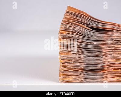 Ein Stapel Euro-Banknoten am Rand eines Tisches, Nahaufnahme, Seitenansicht, auf hellem Hintergrund. Stockfoto