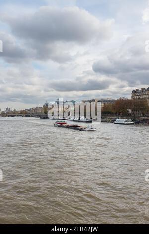 Paris, Frankreich, 2023. Ein Binnenschiff, das flussabwärts auf der seine fährt, von der Pont de la Concorde aus gesehen, mit dem Musée d'Orsay im Hintergrund (vertikal) Stockfoto