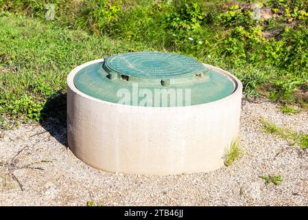 Kanalisationsschacht des ländlichen Klärtanks mit grüner Kunststoffabdeckung, Abwassersystem. Kanalisationsnetze für Landhäuser Stockfoto