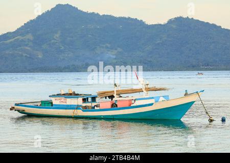 Fischerboot & Blick auf das Festland & Gunung Tumpa an einem östlichen Strand auf dieser Korallen gesäumten Urlaubsinsel. Bunaken Island, Nord-Sulawesi, Indonesien Stockfoto