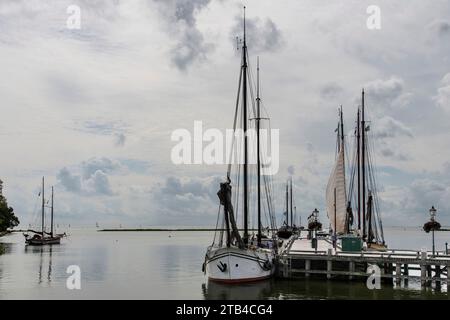 Lange gestreckte Pier mit verankerten traditionellen Booten im Außenhafen von Hoorn in den Niederlanden mit am Horizont Wasser von Markermeer gegen einen Dramat Stockfoto