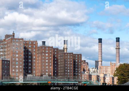 Identische Wohnblocks aus Backstein im East Village, New York City, NY, USA entlang des East River mit den Schornsteinen der Energie im Hintergrund Stockfoto