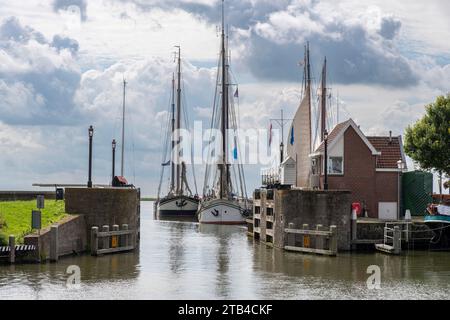Blick vom inneren Hafen von Hoorn in den Niederlanden zum äußeren Hafen mit traditionellen Booten und historischen Gebäuden vor einem dramatischen Himmel Stockfoto
