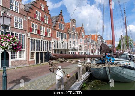Traditionelle Boote, die im Innenhafen von Hoorn in den Niederlanden mit dem Kai von historischen Gebäuden vertäut sind Stockfoto