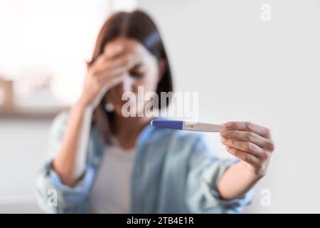 Deprimierte unerkennbare Dame mit negativem Schwangerschaftstest im häuslichen Innenraum Stockfoto