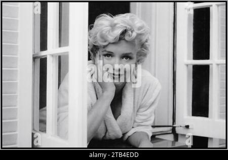 Marilyn Monroe, nachdenkliches verletzliches Public-Porträt, stehend an offenen Fenstern in ungezwungener Pose, in Schwarz-weiß-Hollywood der 1960er Jahre Stockfoto